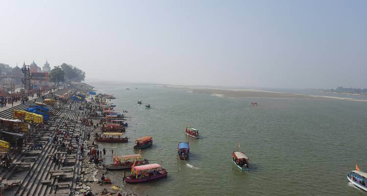 Long riverside with boats and a cityscape along the shore on a clear day.