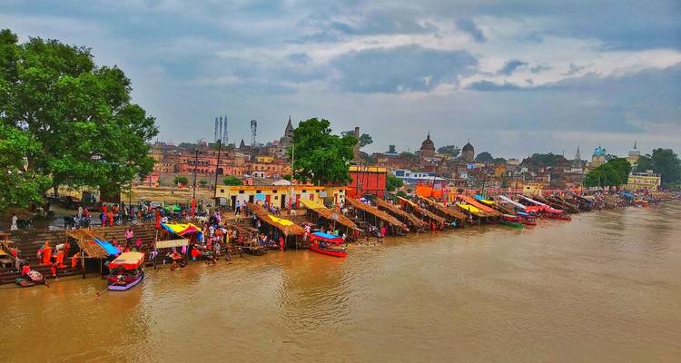 Vibrant riverside scene with boats and colorful market stalls near historic buildings.
