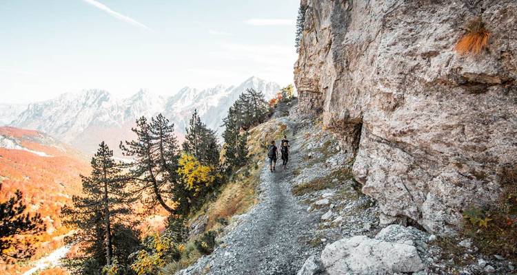 Excursionistas en un sendero montañoso escénico con vistas impresionantes.