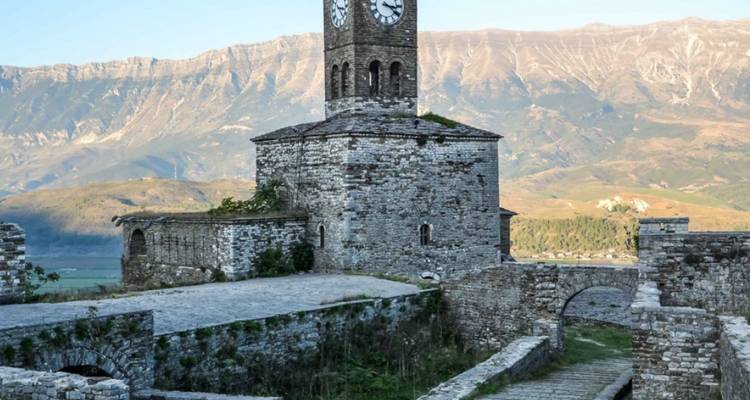 Torre de reloj histórica en Gjirokastra con montañas de fondo.