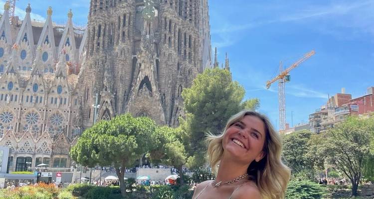 Femme posant près de la Sagrada Família avec un ciel bleu en arrière-plan.