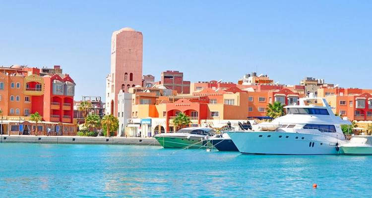 Colorful waterfront of modern Hurghada marina with yachts moored on vivid turquoise water.