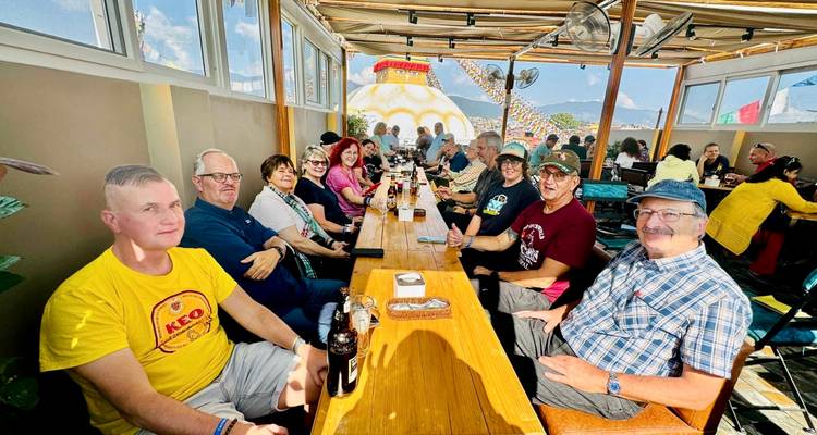 Grupo de turistas sentado en un restaurante en la azotea con vista a una estupa.