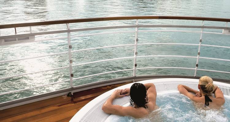 Un couple se détend ensemble dans un jacuzzi sur le pont d'un bateau de croisière avec vue sur les eaux calmes de la rivière