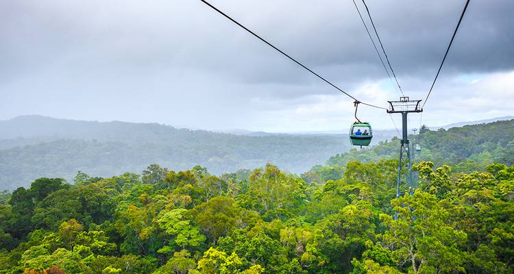 Luchtlijn kabelbaan over een regenwoud met een stormachtige lucht.