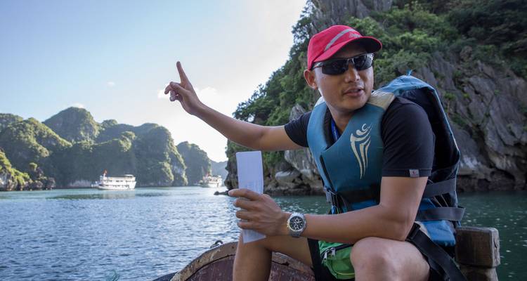 Tourgids op een boot met schilderachtige karstformaties op de achtergrond.