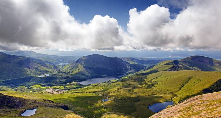 Vista panorámica de verdes valles y lagos bajo picos coronados de nubes en Snowdonia