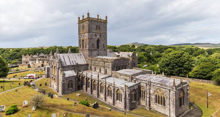 Vaste ensemble de cathédrale médiévale situé dans une campagne verdoyante sous un ciel dégagé