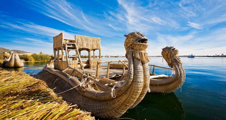 Traditional reed boat on water with a blue sky.