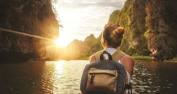 Person on a boat with a scenic view of mountains at sunset.