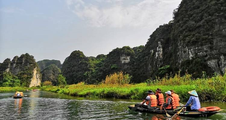 Group of people on boats surrounded by limestone cliffs.