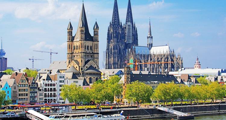 Panoramic skyline of Cologne featuring the soaring twin spires of Cologne Cathedral beside the Rhine.