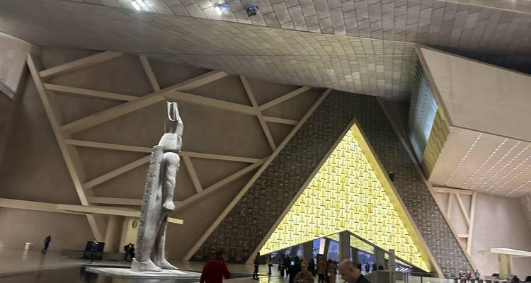 Intérieur de musée avec statues et motifs muraux en forme de pyramide.