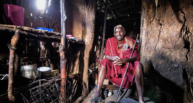 Traditioneller Maasai-Einzelner, der in einer Lehmhütte sitzt.