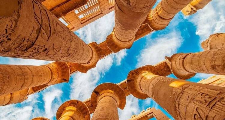 View looking up at the columns of Karnak Temple against a blue sky.