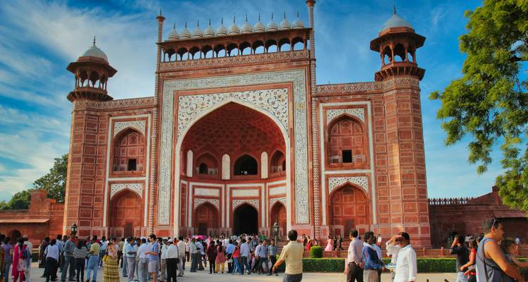 Een grote rode zandstenen poort met een menigte mensen eromheen.