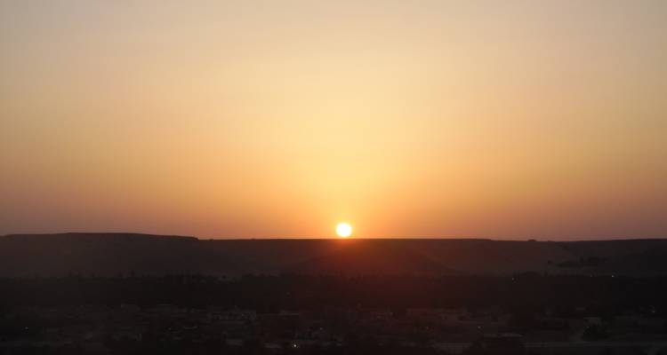 Coucher de soleil sur un paysage désertique avec un horizon en silhouette.
