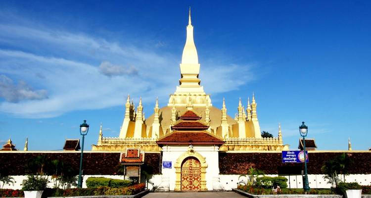 Golden stupa surrounded by a wall and lush gardens.