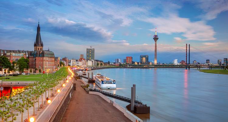 Flussufer-Skyline mit Wahrzeichen-Turm in Düsseldorf in der Abenddämmerung.