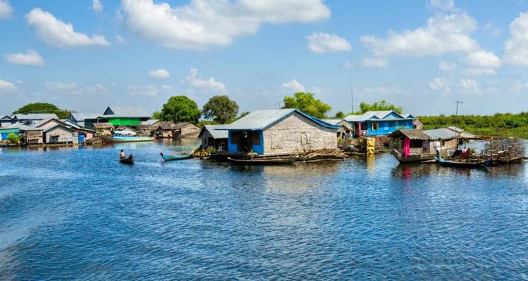 Floating houses on a river under a bright blue sky.