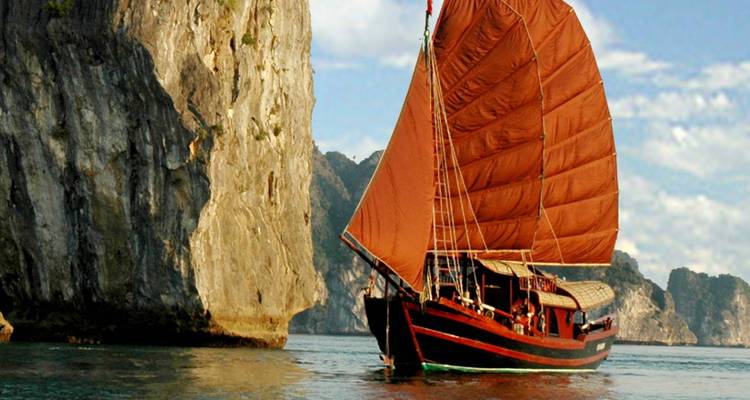 Un bateau jonque traditionnel naviguant entre des karsts calcaires.