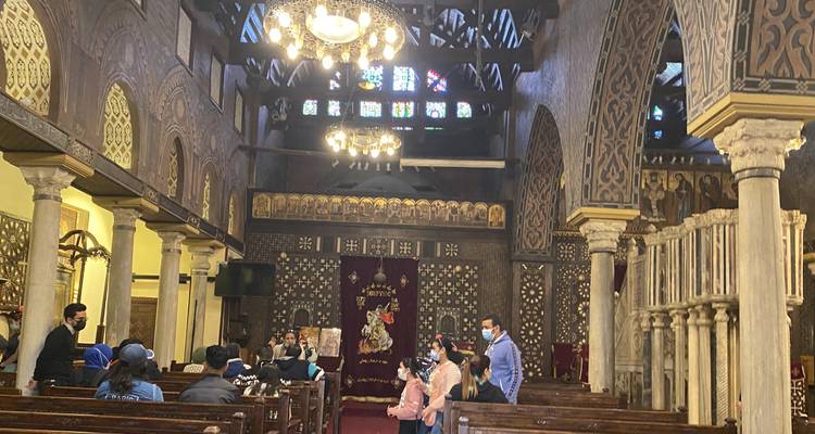 People sitting inside a church with ornate decorations and stained glass windows.