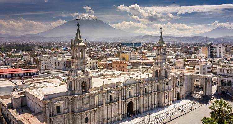 Luftaufnahme der Kathedrale von Arequipa mit dem Vulkan Misti, der sich hinter der Stadtsilhouette erhebt.