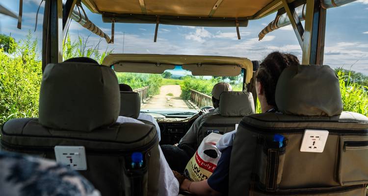 People inside a safari vehicle on a dirt road.