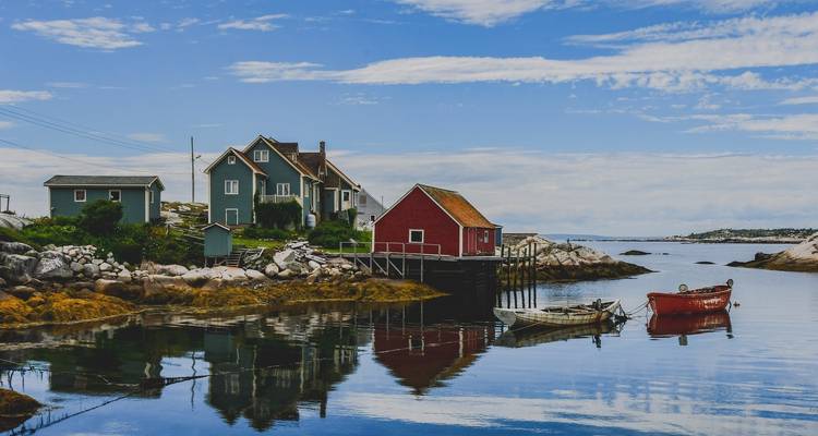 Scène côtière avec des maisons colorées et de petits bateaux dans l'eau.