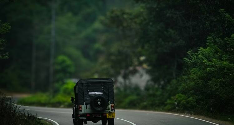 Jeep driving along a winding forest road in the Western Ghats.
