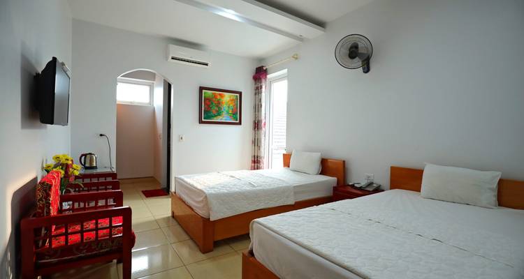 Chambre d'hôtel avec deux lits, télévision et décoration minimaliste.