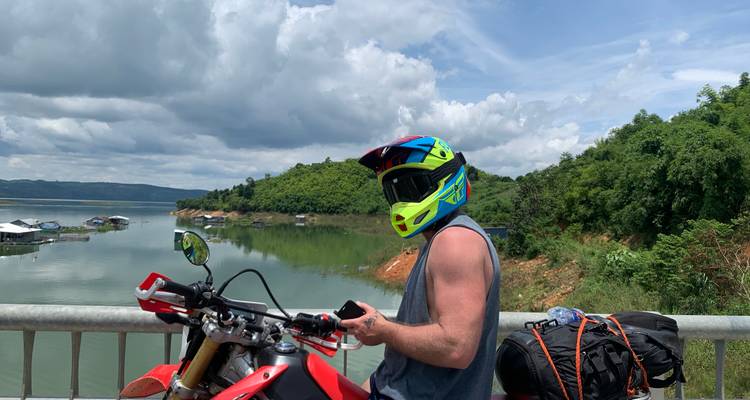 Homme sur une moto contemplant un paysage luxuriant.