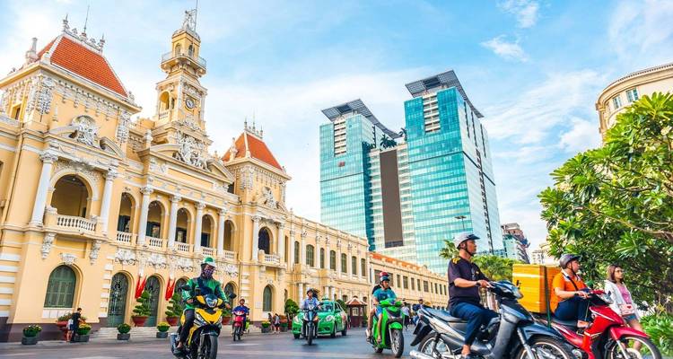 Motos passant devant un bâtiment historique dans une ville animée.