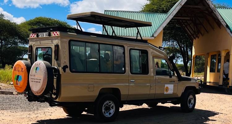 Safari vehicle parked at a gate with people inside.