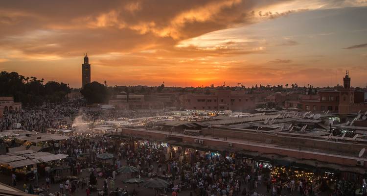 De zonsondergang kleurt de hemel boven het drukke Jemaa el-Fnaa marktplein in Marrakesh.