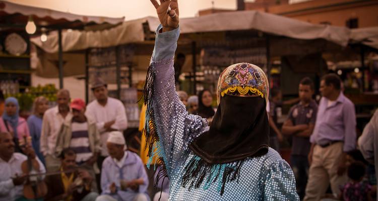 Artista en atuendo tradicional con una multitud en el fondo.