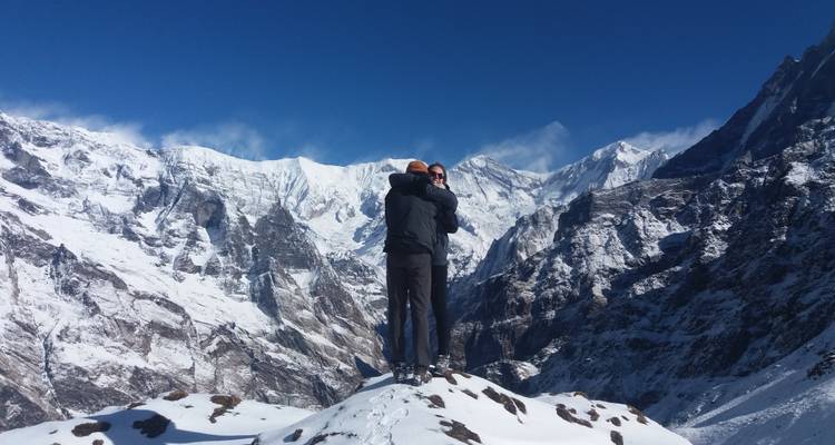 Een stel dat elkaar omhelst op een besneeuwde bergtop met de Himalaya op de achtergrond.