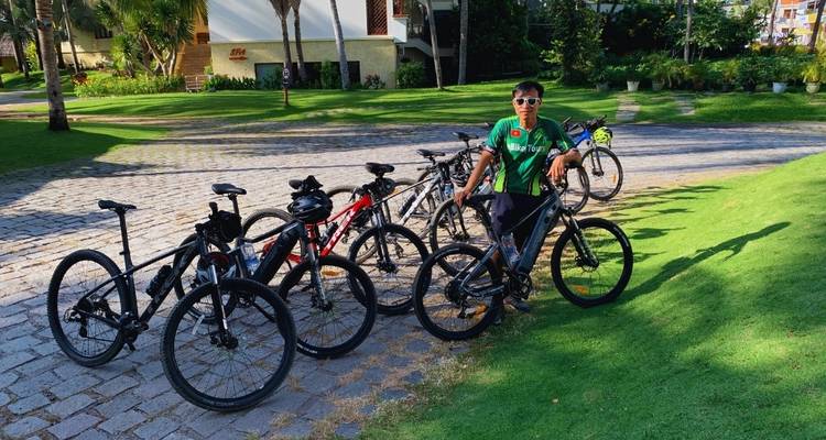 Persoon die staat met fietsen op een geplaveide pad met groen eromheen.