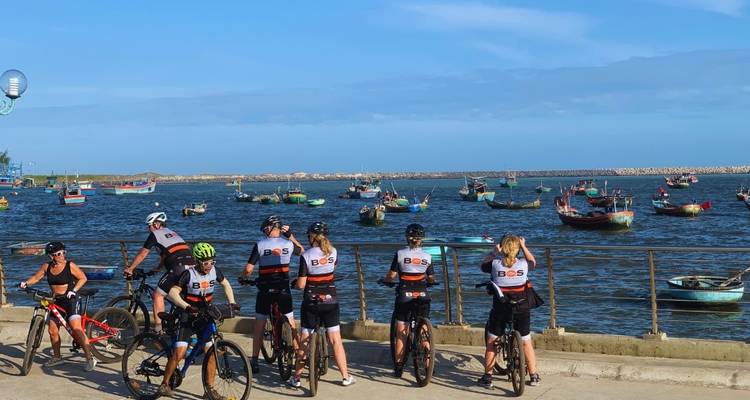 Fietsers bij een pier met boten op het water.