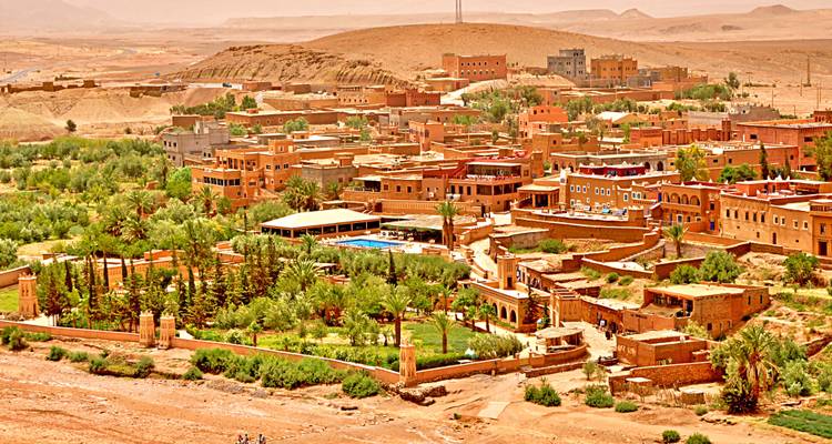 Luchtfoto van een kleine stad omringd door woestijn en begroeiing.