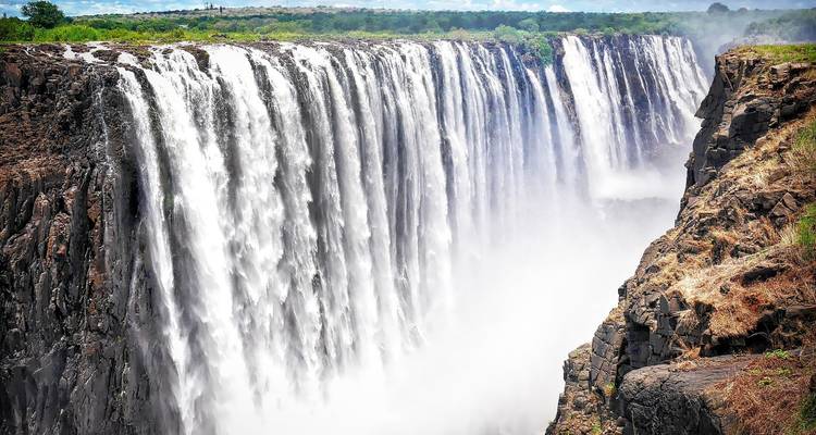A wide view of powerful waterfalls surrounded by lush greenery.