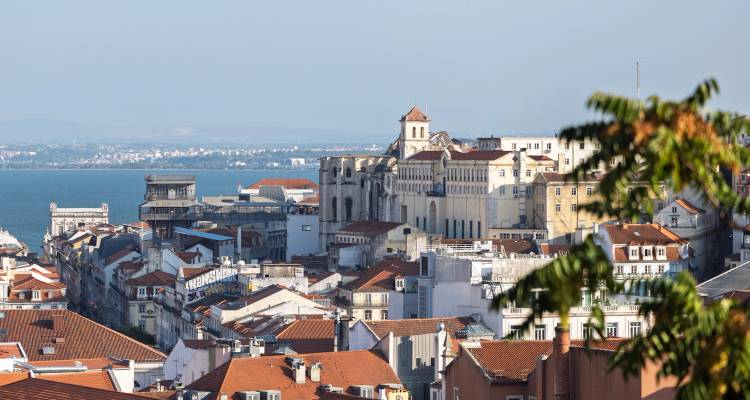 Panoramic view over Lisbon’s terracotta rooftops toward the Tagus River and distant hills.