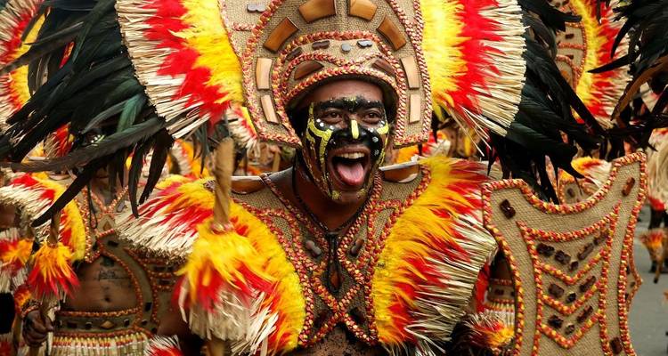 Nahaufnahme einer Person in leuchtender Festivalkleidung und Gesichtsbemalung.