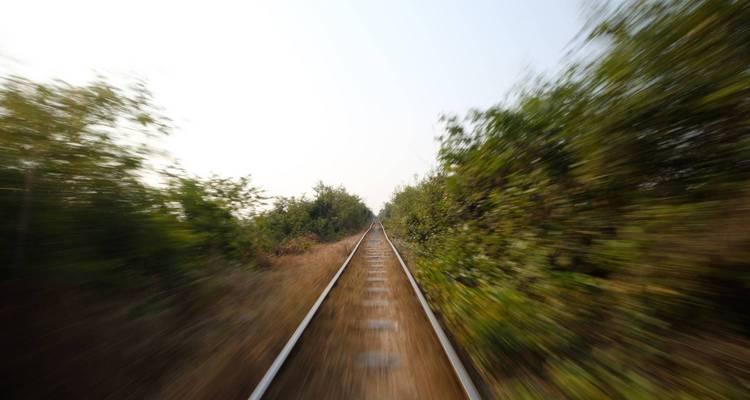 Perspective avec effet de flou de mouvement regardant directement vers le bas des voies ferrées se déplaçant rapidement à travers la campagne.