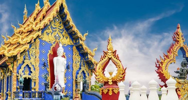 El vívido Templo Azul en Chiang Rai que muestra motivos de dragones dorados y una estatua de Buda blanca.