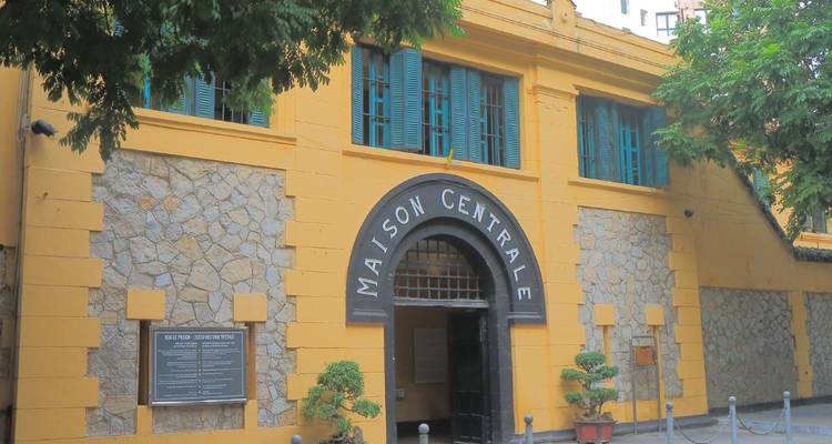 Gele gevel van Hoa Lo Prison (Maison Centrale) met turquoise luiken en gewelfde ingang.