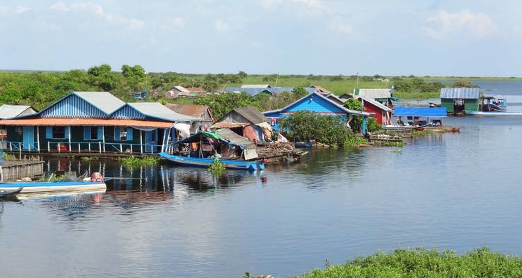 Rij met gekleurde drijvende huizen en boten langs een rustig meer in Cambodja's Tonle Sap-regio.