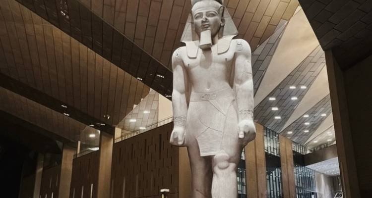 Statue d'un pharaon de l'Égypte antique dans un bâtiment moderne.