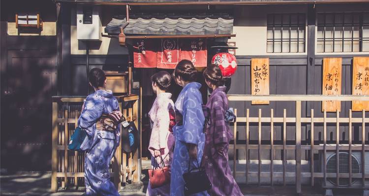 Frauen in traditionellen Kimonos, die vor einem Schrein gehen.