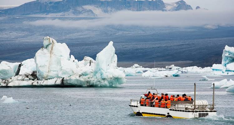 Touristen auf einem Boot mit Eisbergen im Hintergrund.